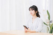 © garage38 - 部屋でスマホを使う若い女性