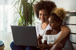© lordn - African American family. Mother and daughter using laptop computer at home or learning