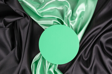 Wall Mural - Circle platform podium on elegant black and light green color background with drapery and wavy folds of silk satin material. Pastel mock up background for cosmetic product presentation. Top view