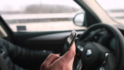 Poster - The driver uses the navigation in the mobile phone while driving. He presses the screen with his finger, controls the vehicle with his hand. Find the right address before meeting.