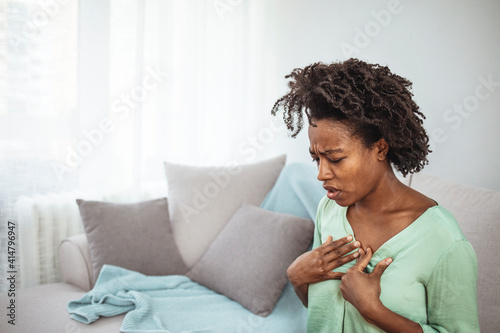 Pressure in the chest. Close-up photo of a stressed woman who is suffering from a chest pain and touching her heart area. Young woman with heart problem holding chest.