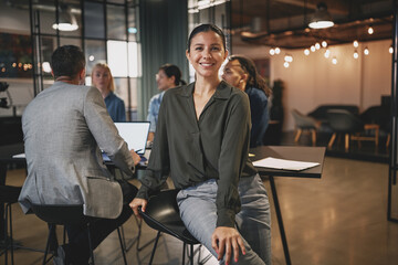 Wall Mural - Smiling businesswoman sitting with colleagues at an office table