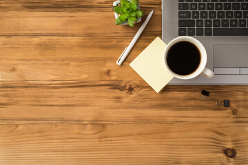 Overhead above close up flat lay view photo image of laptop keyboard green succulent mug of beverage with yellow note paper isolated brown wooden backdrop with empty blank space