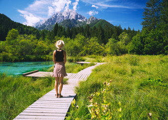 Wall Mural - Travel, Freedom, Lifestyle concept. Young woman enjoying green nature outdoors. Amazing view on Zelenci (into English means - green) natural reserve in Slovenia, Europe. People in nature background.