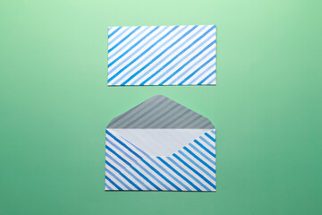 Wall Mural - Open striped envelope on green background.