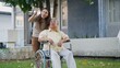 © sorapop - Disabled senior man on wheelchair with daughter, Happy Asian generation family having fun together outdoors backyard, Care helper young woman walking an elderly man smiling and laughed