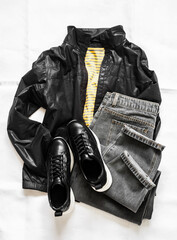 Wall Mural - Women's clothing - yellow cotton striped t-shirt, gray mom jeans, black windbreaker and black leather sneakers on a light background, top view