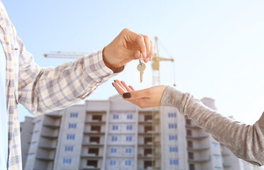 Canvas Print - Real estate agent giving a key from new house to woman near unfinished building