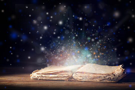 Open magic book on dark background