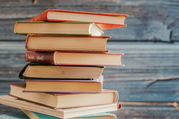 Poster - Stack of books in the colored cover lay on the wood table  with blue wood backround. Education learning concept