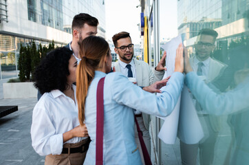 Wall Mural - Coworkers standing outside in front of office buildings discuss about business plan.