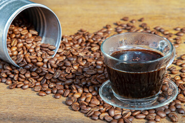 A cup of black coffee and coffee beans roating around on the wooden background with copyspace for your text. Alternative coffee for living life, Coffee style, Selective focus.