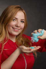 a blonde girl with an overweight plus size, in a red overall posing on a dark Studio background. holding set for Cosmetic procedure of hair removal wax,