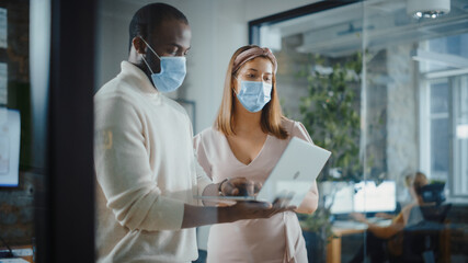 Wall Mural - CTO and Chief Strategist Wearing Face Masks Talking About Business Growth, Analyze Data, Use Laptop Computer. Two Diverse Professionals Discuss Revenue Increase, Market Disruption, Planning Strategy