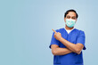 healthcare, profession and medicine concept - indian doctor or male nurse in uniform and face protective medical mask showing something imaginary over blue background