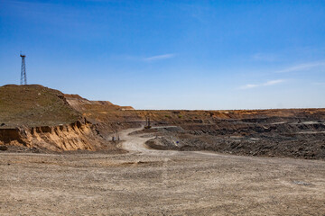 Wall Mural - Copper ore open-pit mining. Quarry panorama. Electric mast and quarry machines on blue sky background.