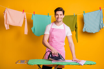 Photo of young happy cheerful positive good mood man ironing clothes on board isolated on yellow color background