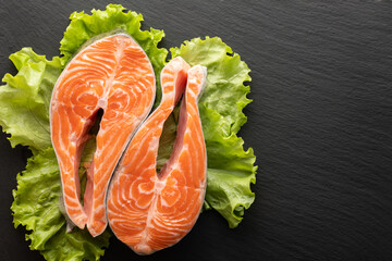 Wall Mural - fresh salmon steak on lettuce leaf, stone background, flat lay, place for text