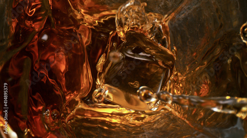 top of view of pouring whiskey in the glass with ice cubes on black table background © Lukas Gojda