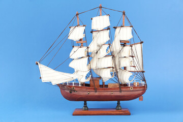 Sticker - Miniature model of old ship with white sails on blue background