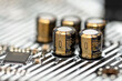 A macro shot of five capacitors in a metal housing, soldered to the motherboard of a desktop computer.