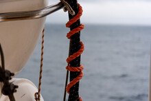 An Orange Ship Rope Is Tied To A Lifeboat With A Maritime Knot On The Railing Of A Passenger Ship - In The Background You Can See The Deep Blue Sea On A Beautiful Summer Day - Concept Of Rescue