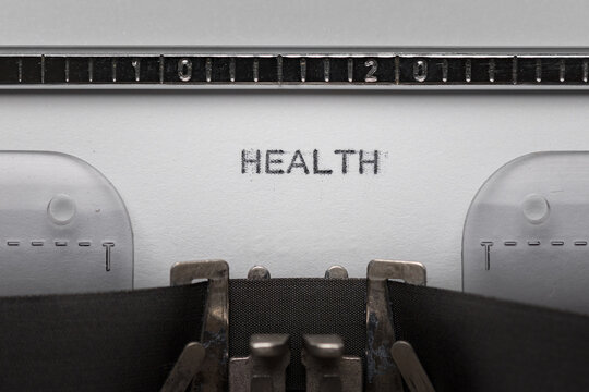 Typing text HEALTH on vintage manual typewriter. Close up of writes word on white paper. Shot in macro.