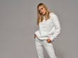 © kiuikson - Beautiful young blonde woman wear of white set of track suit over gray background