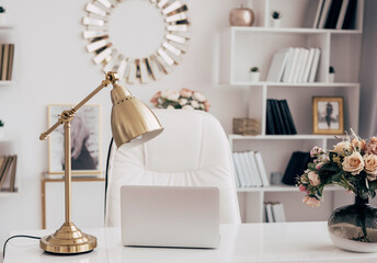 female office with a workspace desk in a light modern style with white furniture with laptop on table