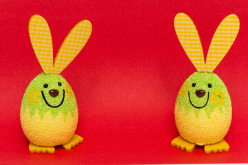 Closeup shot of two egg-shaped bunny dolls isolated on a red background