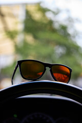 Poster - Fashion sunglasses placed on the steering wheel of a car