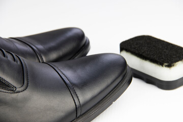 black classic beautiful shoes and sponge on a white background, close up. shoe care, shoe cleaning.