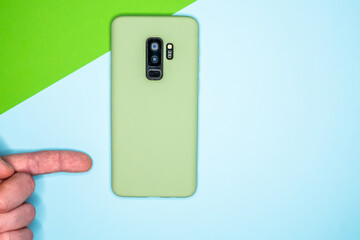 Poster - Hand showing a light green mobile phone put vertically in the background of blue and green colors