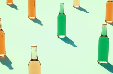 Leinwandbilder - Closeup of various color glass bottle rows against light blue/green surface.