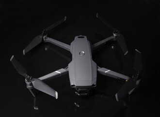 New dark grey drone quadcopter with digital camera and sensors flying isolated on black background