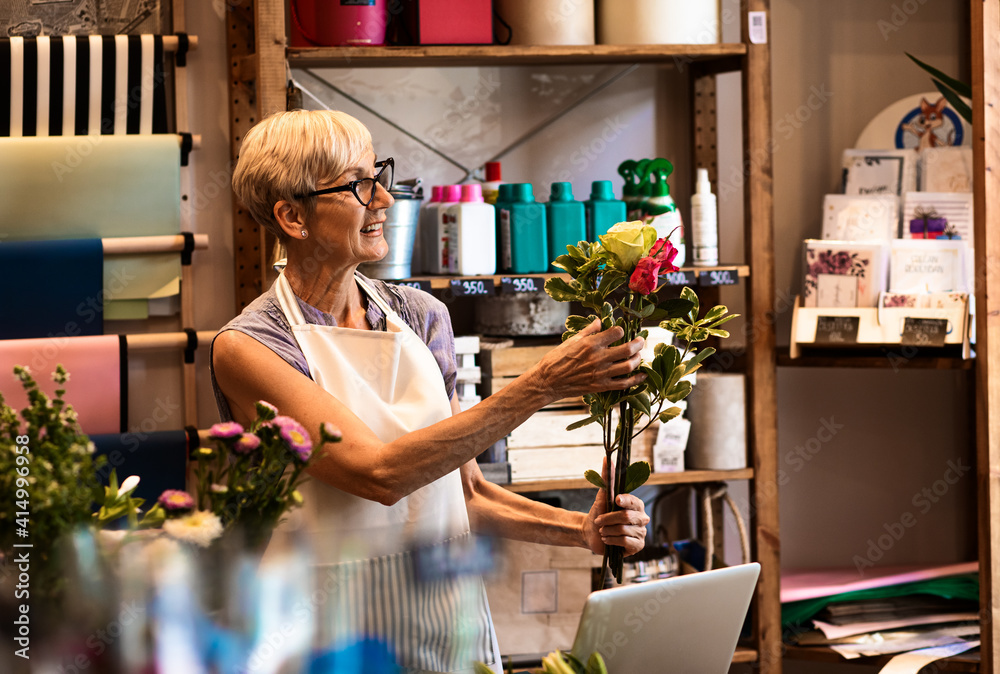 Senior woman working in flower shop making bouquet. - obrazy, fototapety, plakaty 