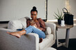 © Gerald R Carter Jr/Creative Flame - Black woman relaxing and comfortable on couch looking at cellphone