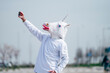 Man wearing unicorn mask taking a photo with smartphone