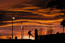 Carefree Man Dancing While Standing On Bridge During Sunset