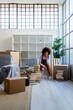 © Giorgio Fochesato/Westend61 - Afro woman with hand on chin against bookshelf in new home