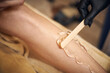 © Taras Grebinets - Closeup of woman's leg and aesthetician's hand applying a transparent gel with spatula before laser epilation