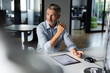 © peter scholl/Westend61 - Thoughtful businessman looking away while sitting by desk at office