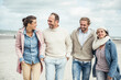 © Uwe Umst√§tter/Westend61 - Group of adult friends walking side by side along sandy beach