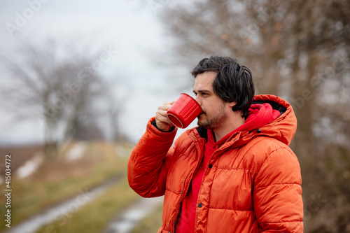 Hipster guy with red mug drink a coffee in countryside © Masson