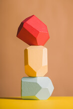 Wooden Blocks In Shapes Of Gems Of Various Colors Stacked On Beige Background In Studio