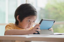 Child Playing Game On Tablet With Serious Face