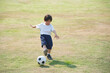 © lalalululala - Asian boy kicking football on the field