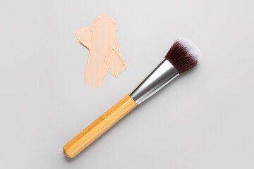 Sample of makeup foundation and brush on light background