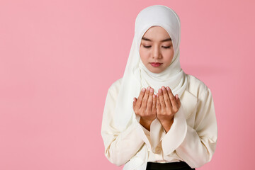 Wall Mural - Portrait of young and cute Asian Islamic woman rise hands in praying gesture in calm and concentrate manner.