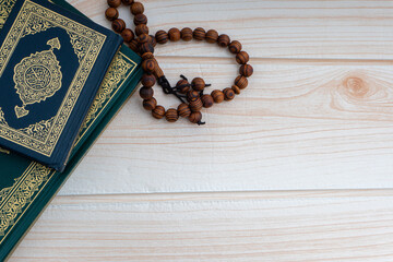 Wall Mural - Holy Quran with arabic calligraphies translation meaning of Al-Quran and Rosary or Tasbih on wooden background. Ramadan,Hajj, Islamic and Copy Space concept